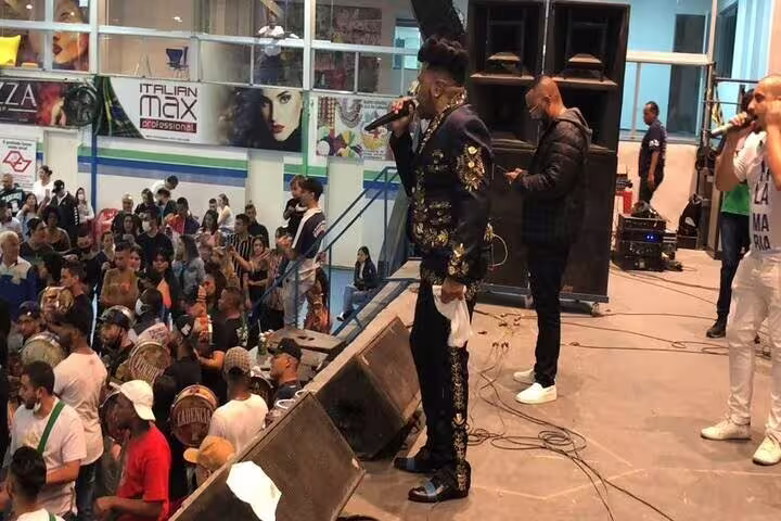 Energetic singer performing on stage at São Paulo Carnaval rehearsal with an engaged audience and lively atmosphere.
