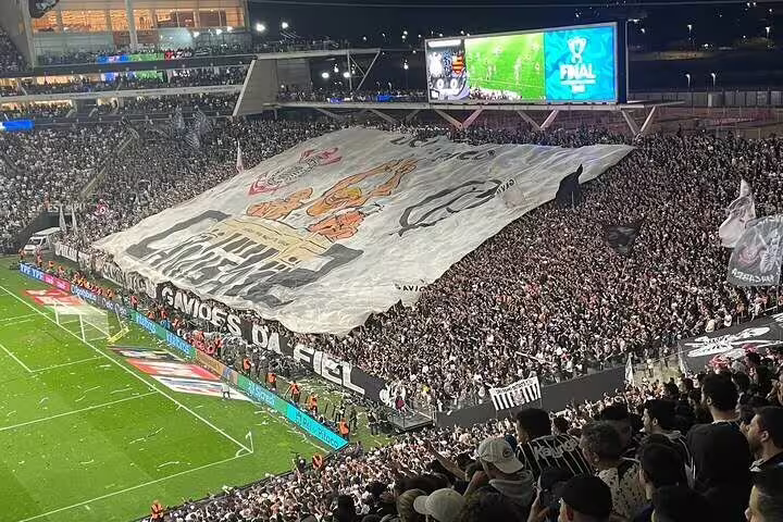 Enthusiastic crowd displays a giant banner in São Paulo's stadium, capturing the essence of a live football experience.