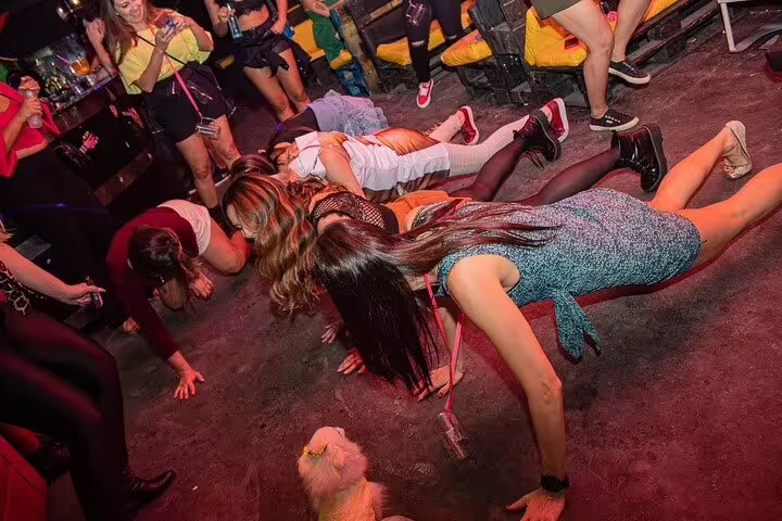 Energetic group dancing on the floor of a vibrant São Paulo nightclub during a lively pub crawl.