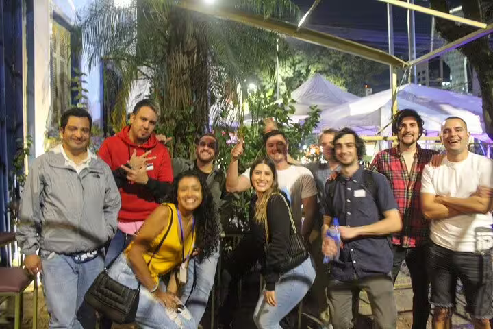 Smiling group of friends posing outdoors during a São Paulo nightlife pub crawl event.