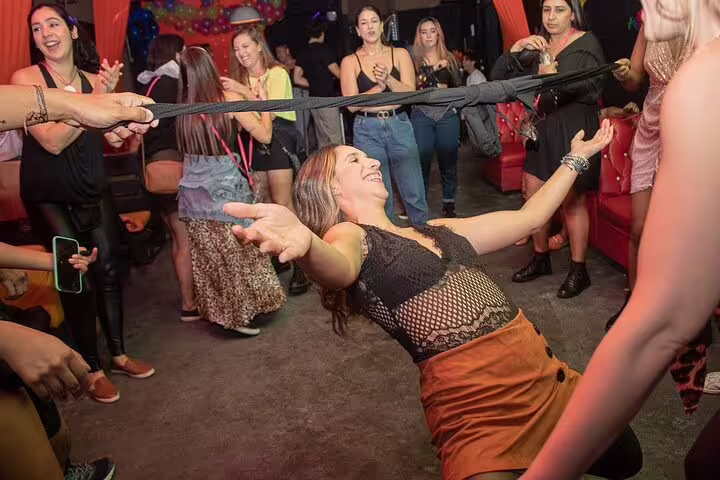 Woman having fun at a São Paulo pub crawl, participating in a limbo game with a joyful crowd.