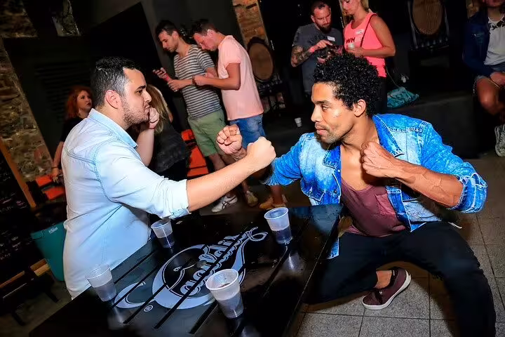 Two men playfully arm wrestling in a bustling São Paulo pub, showcasing the city's energetic nightlife.
