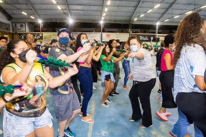 Participants enthusiastically shake tambourines at a vibrant São Paulo samba school rehearsal.