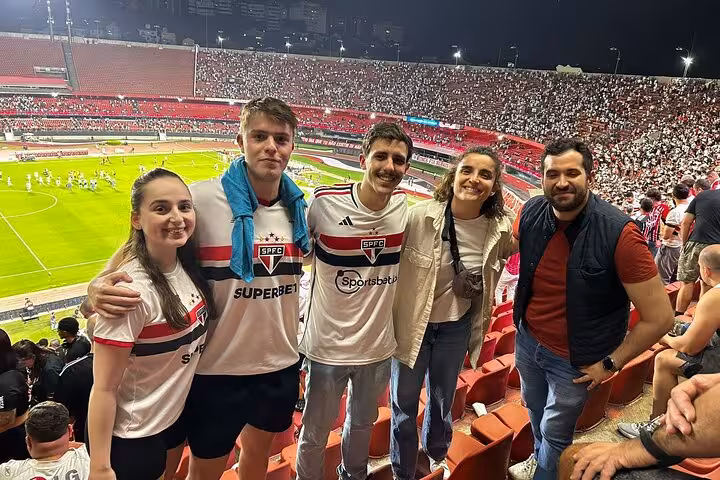 Group of travelers with local guide at Morumbi Stadium stands during a São Paulo soccer match experience