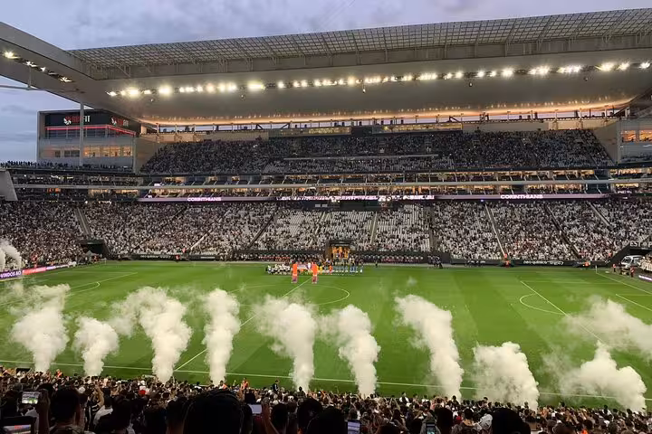 Packed São Paulo football stadium with pre-match smoke and fans, part of a local soccer game experience tour