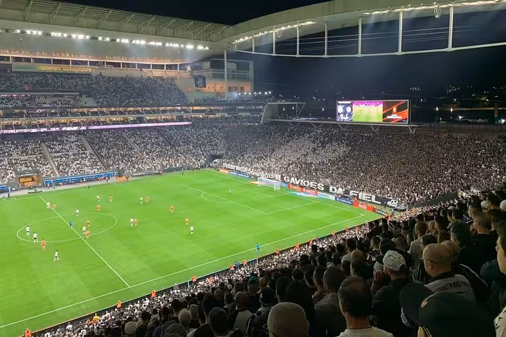 Night view of a packed São Paulo stadium during a live soccer match, ideal for local fan game-day tour