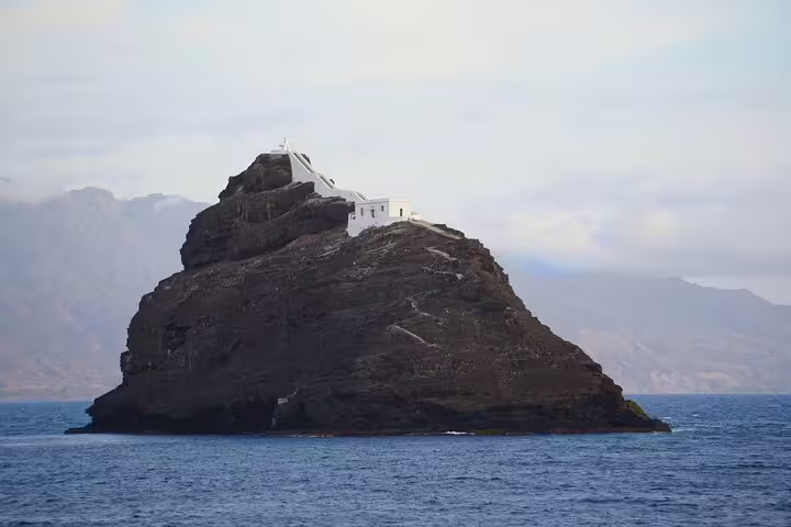 Rocky islet with white chapel off São Vicente, scenic stop on airport to Baía das Gatas private transfer