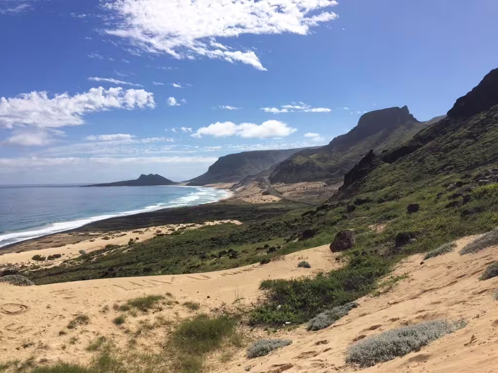 Scenic view of São Vicente coastline with sandy beaches and lush hills under a clear blue sky, ideal for half-day tours.