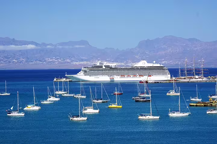 Cruise ship and yachts anchored in São Vicente harbor with stunning mountain backdrop on a guided tour.