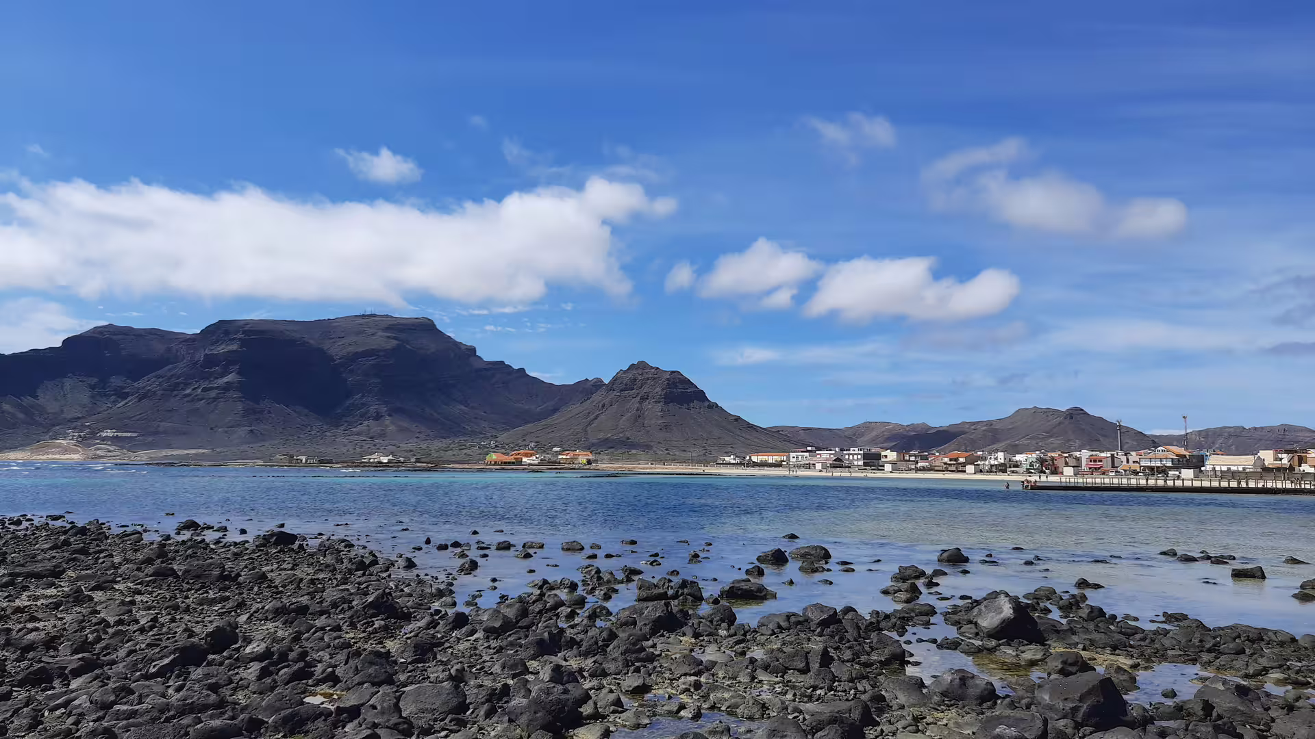 Rocky coastal landscape with distant mountains and clear skies on São Vicente Island, ideal for exploration tours.