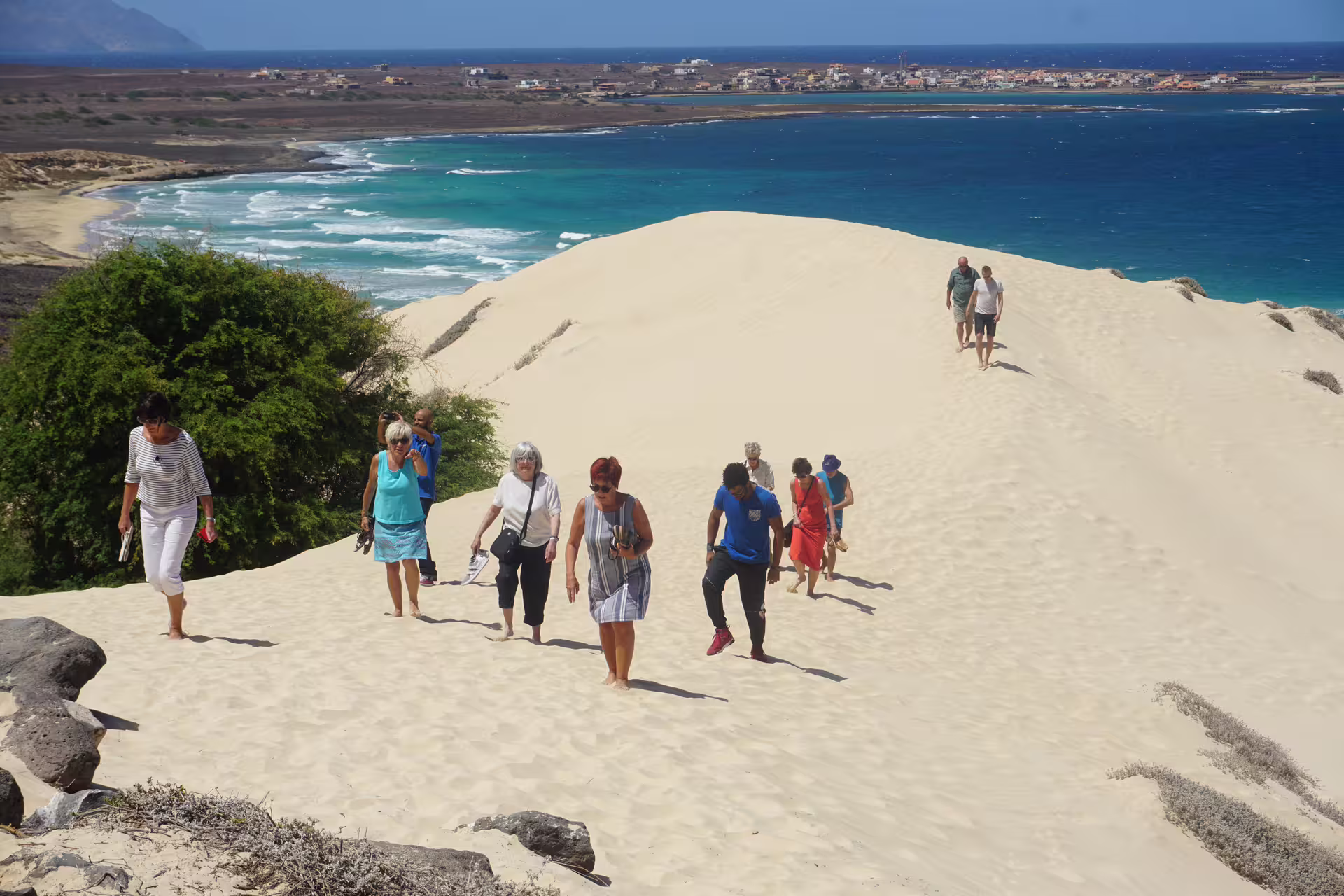 Tourists hiking on sand dunes with ocean views on São Vicente Island during a full-day tour from Praia.