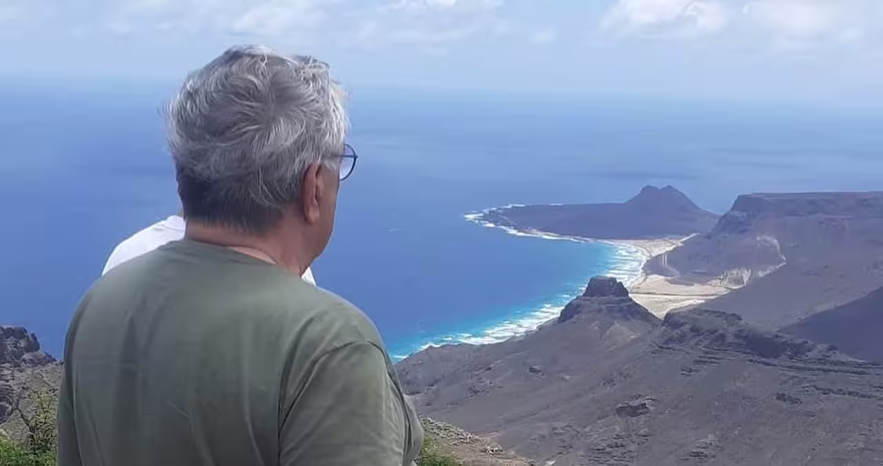 Traveler enjoys breathtaking coastal views of São Vicente's rugged landscape and azure waters during a Mindelo shore excursion.