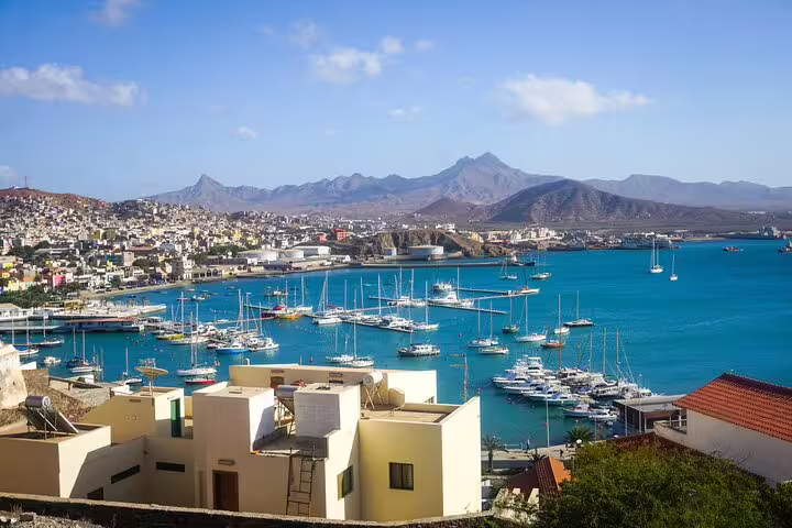 Scenic view of São Vicente harbor with boats and mountains under a clear blue sky, ideal for a snorkel tour departure.