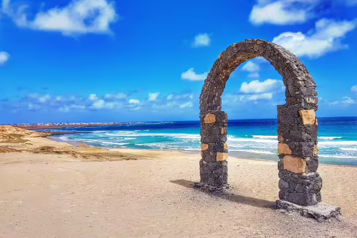 Stunning stone arch on sandy São Vicente beach with vibrant blue ocean, perfect for exploring Cape Verde's scenic beauty.
