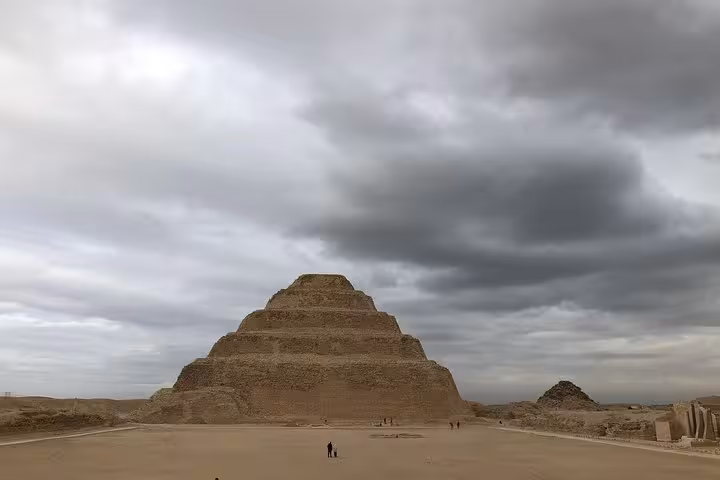 Step Pyramid of Saqqara under dramatic clouds, included on all-inclusive private tour from Cairo Airport to Giza
