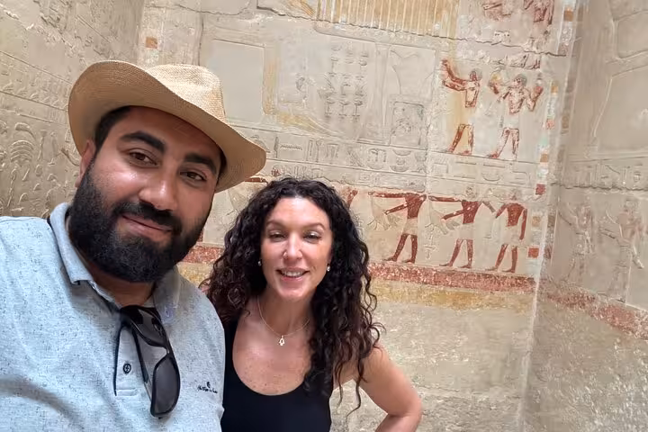 Travelers with Egyptologist guide inside Saqqara tomb, viewing ancient wall reliefs on a private tour from Cairo