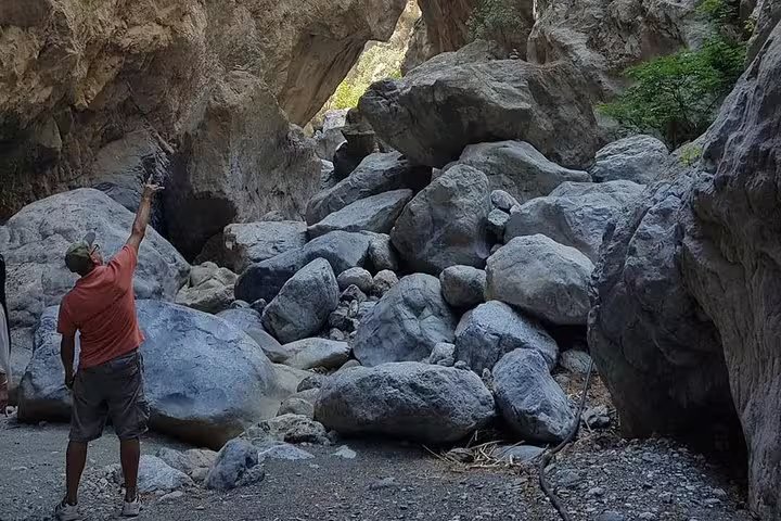 Hiker pointing at towering rock formations in the rugged landscape of Sarakina Gorge, Crete.