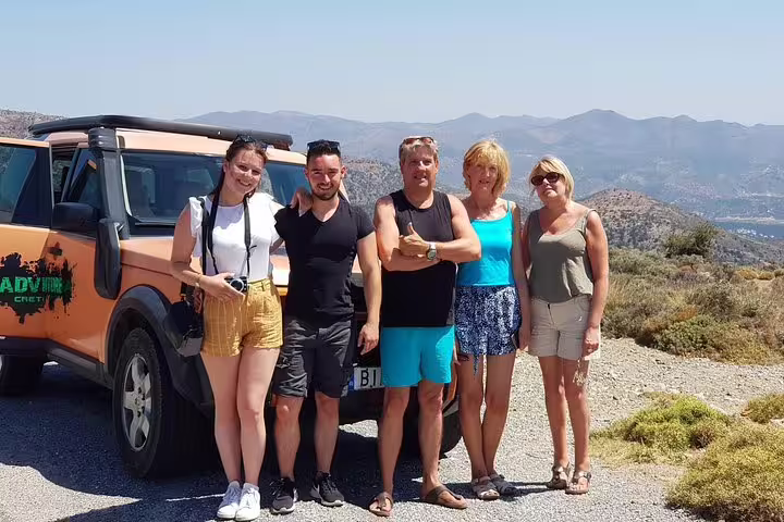 Group of tourists enjoying a scenic stop with a rugged vehicle on a South Coast mountain tour in Kritza.