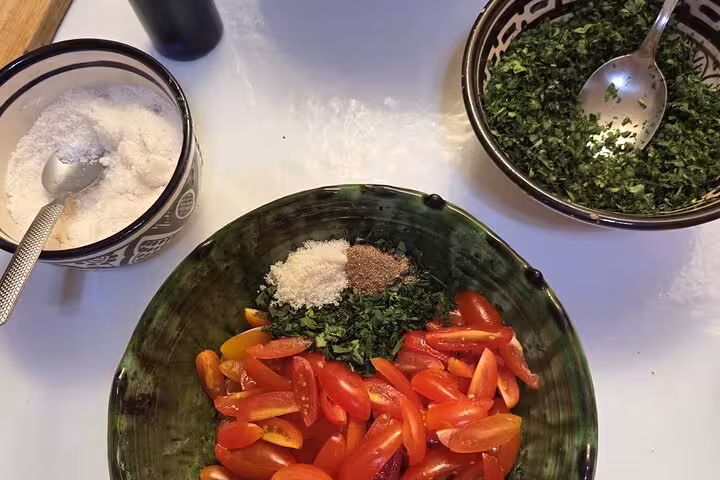 Preparation of chopped tomatoes and herbs with spices for Sardin Tawa Cooking Class Marrakesh dish.