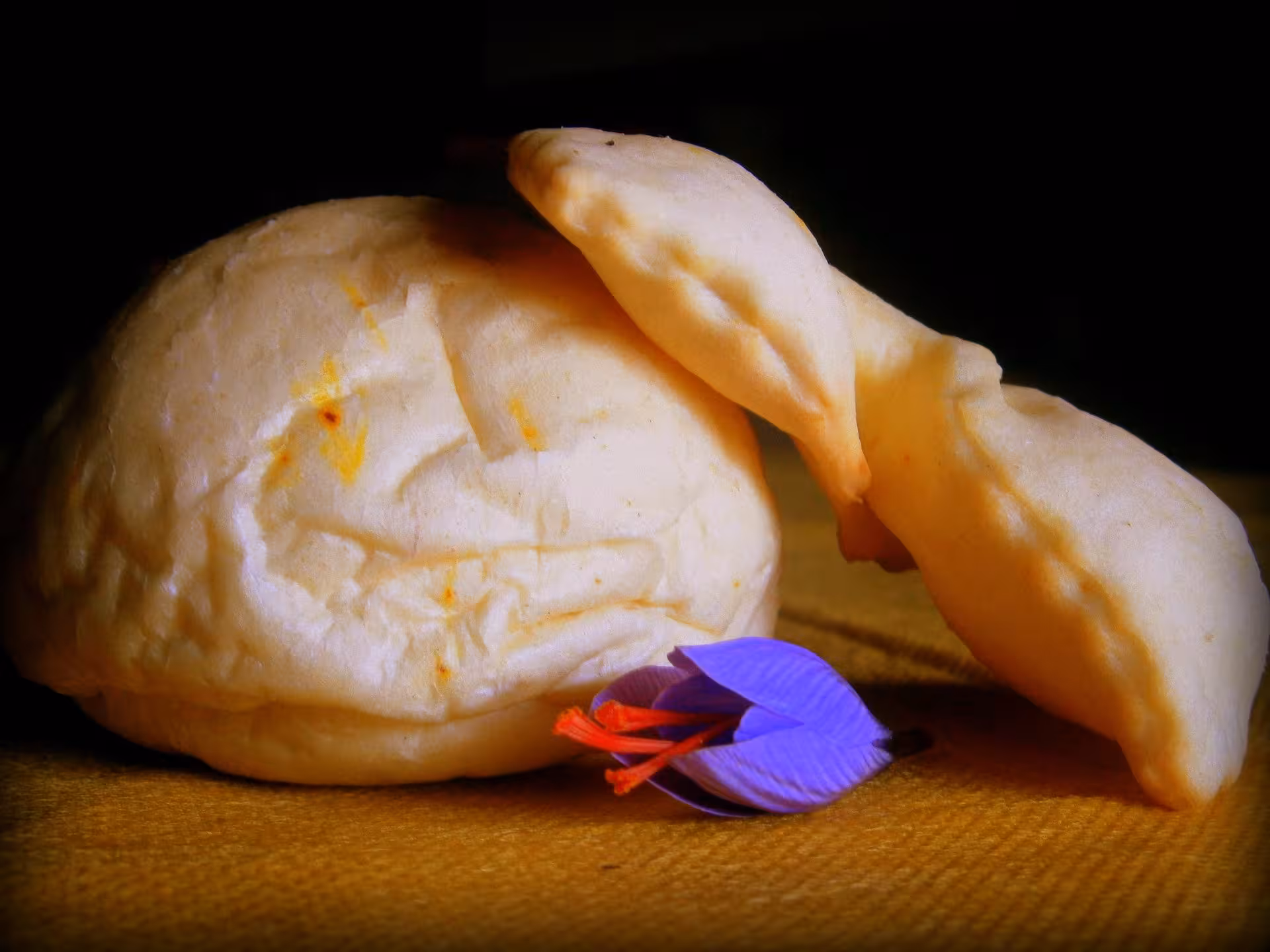 Freshly baked Sardinian bread paired with vibrant saffron flowers, highlighting a culinary experience in Olmedo.