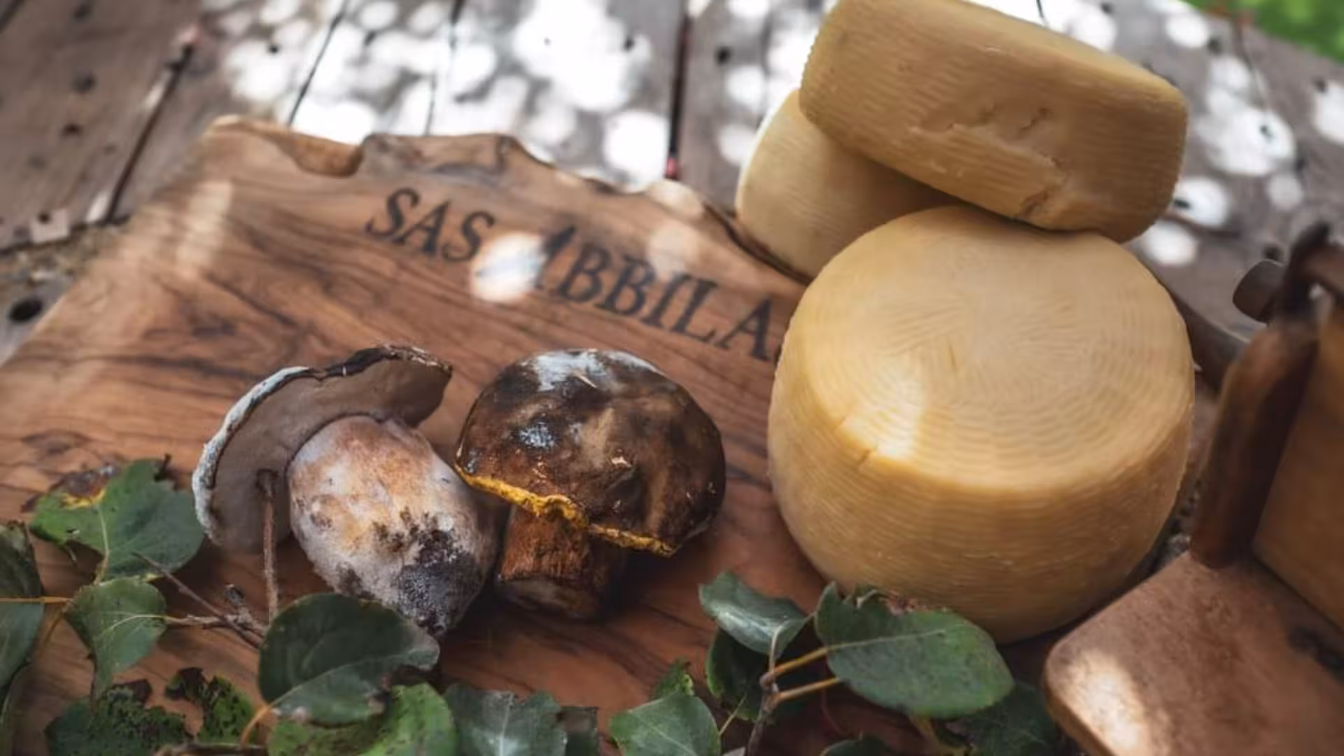 Rustic wooden board with Sardinian cheese and mushrooms, showcasing authentic Bonorva farm produce.