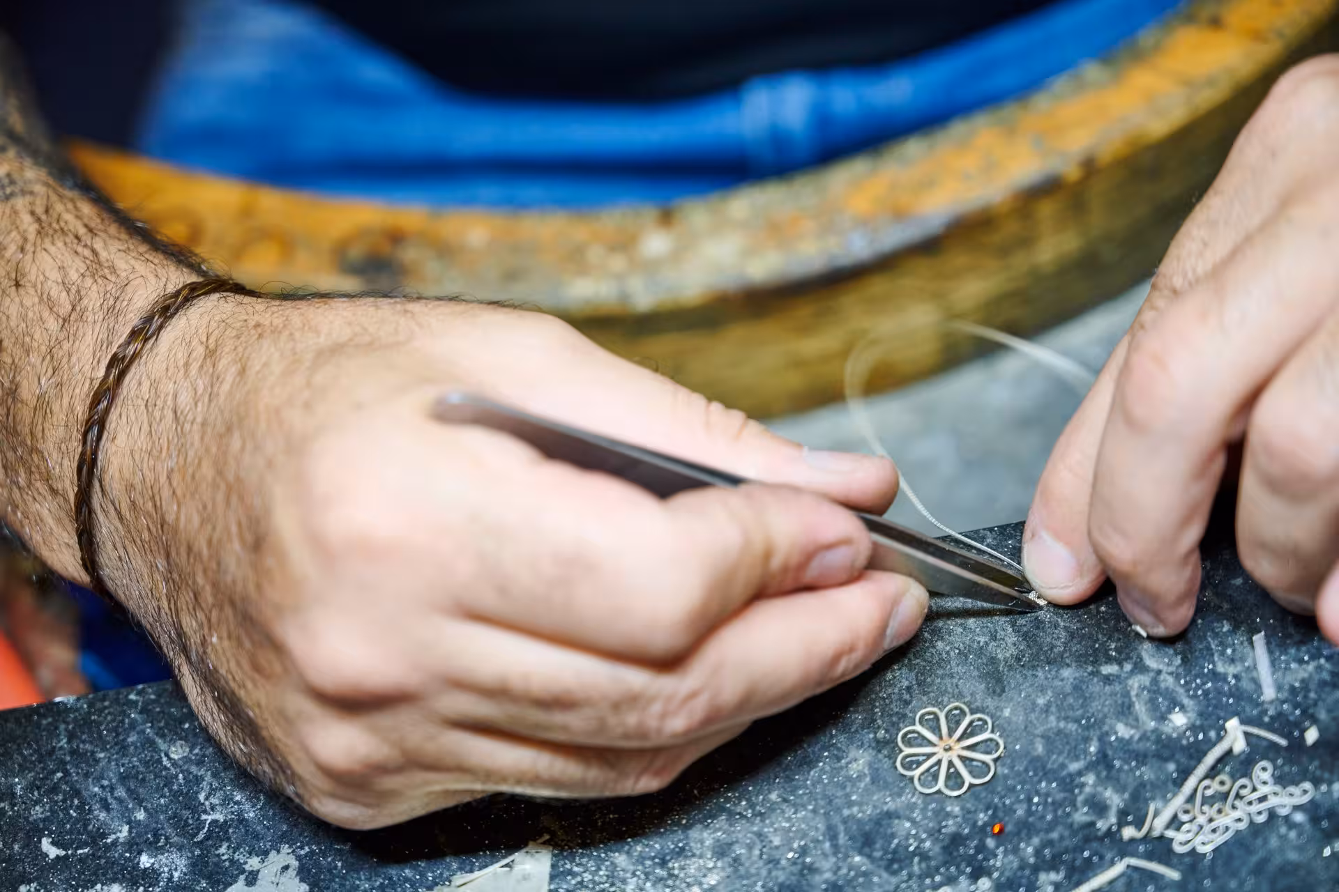 Craftsman meticulously creating intricate Sardinian filigree design with tools in Dorgali's goldsmith lab.