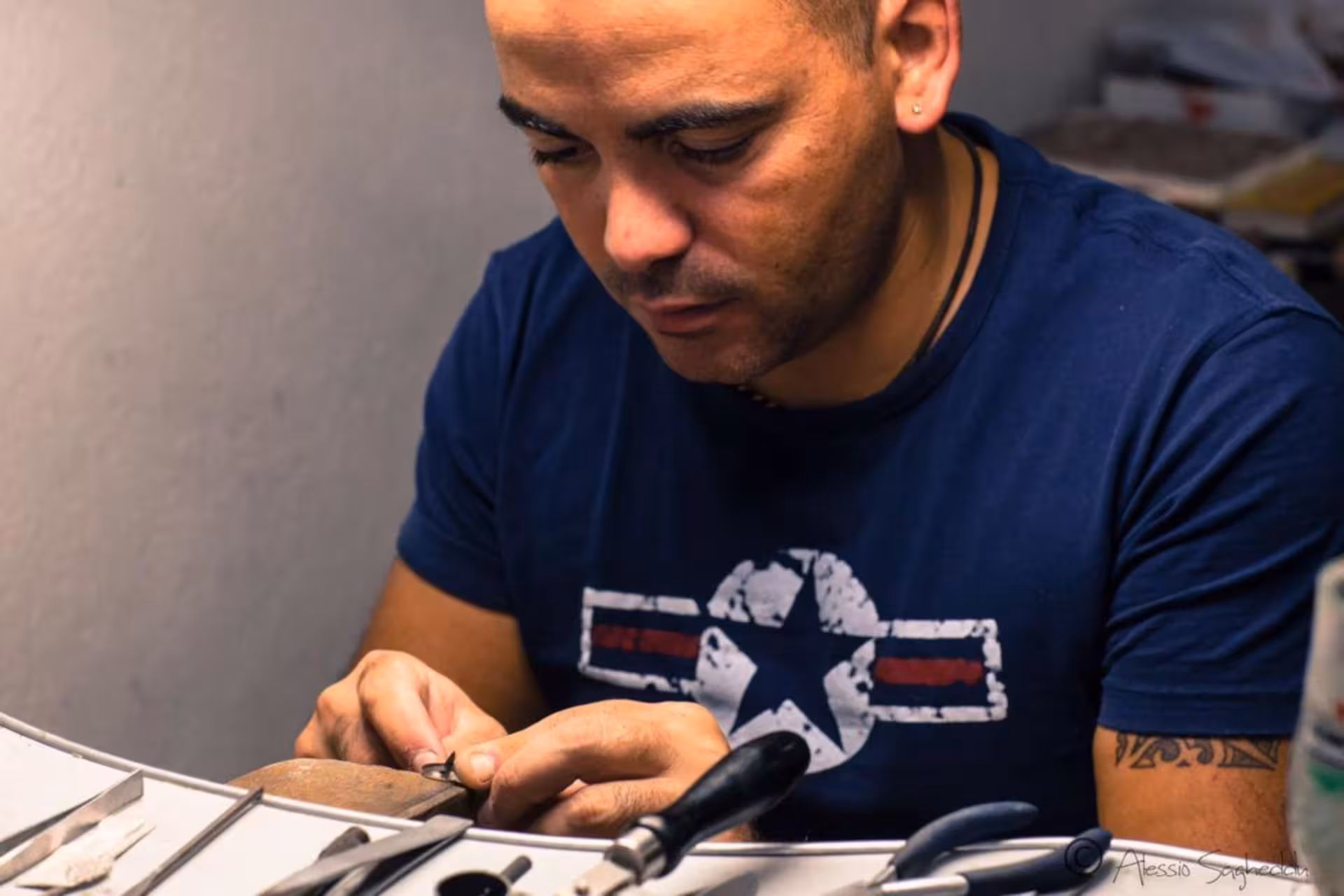 Jeweler in Dorgali meticulously working on Sardinian filigree piece, highlighting craftsmanship.
