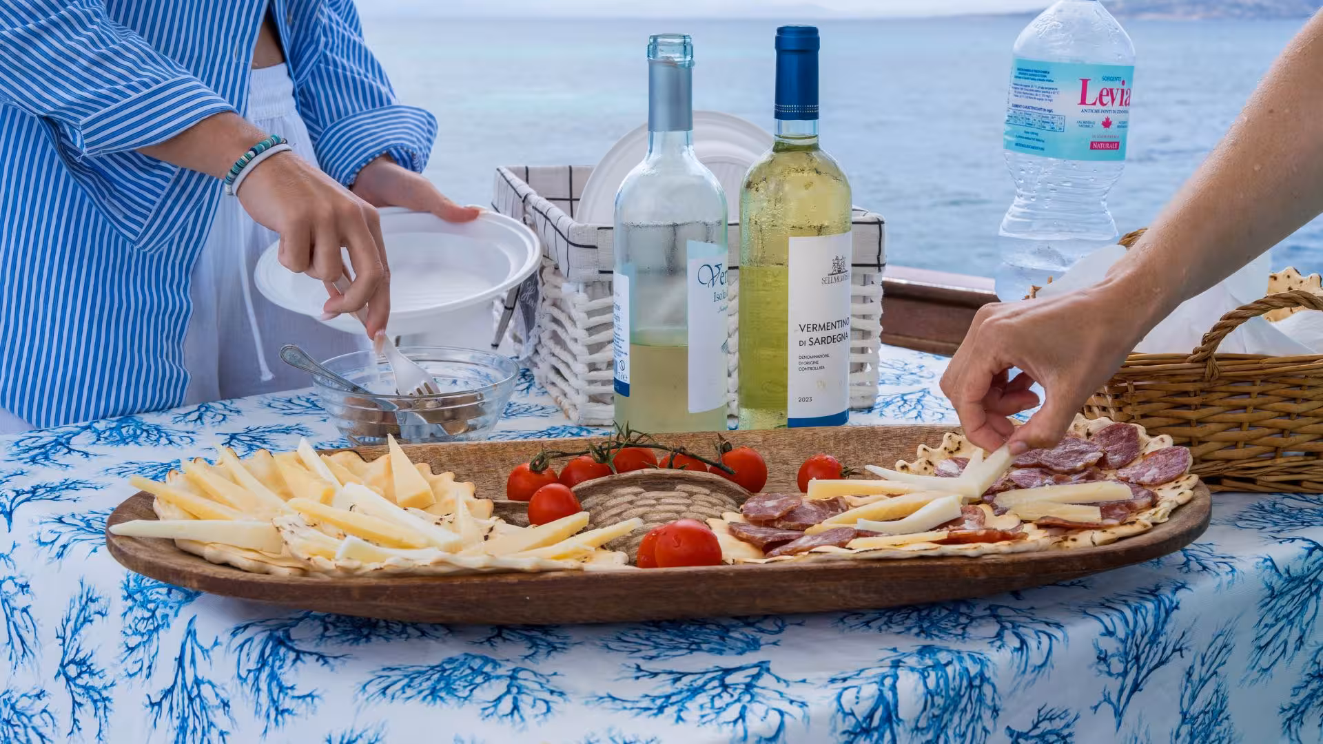 Gourmet platter with Sardinian cheese, salami, and Vermentino wine on Asinara sailing tour.