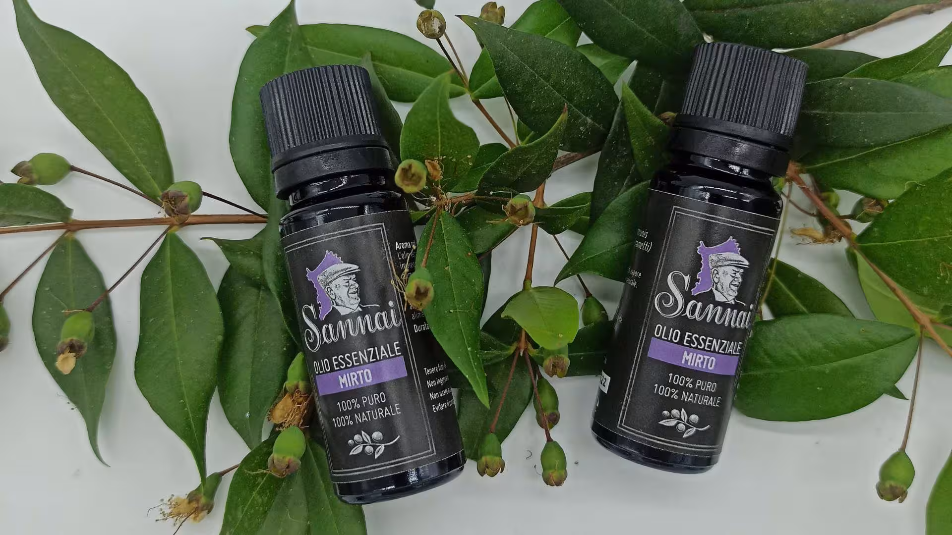 Essential myrtle oil bottles with fresh myrtle leaves, showcasing Sardinian craftsmanship.