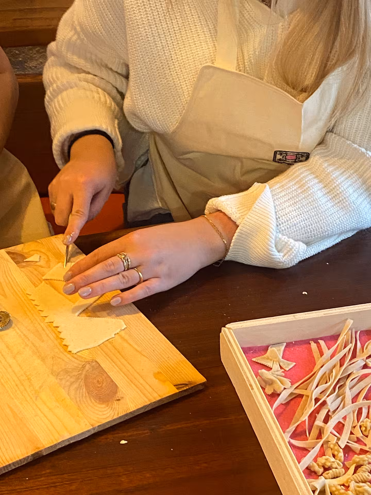 Participant crafting pasta during hands-on Sardinian cooking class in picturesque Olbia village.