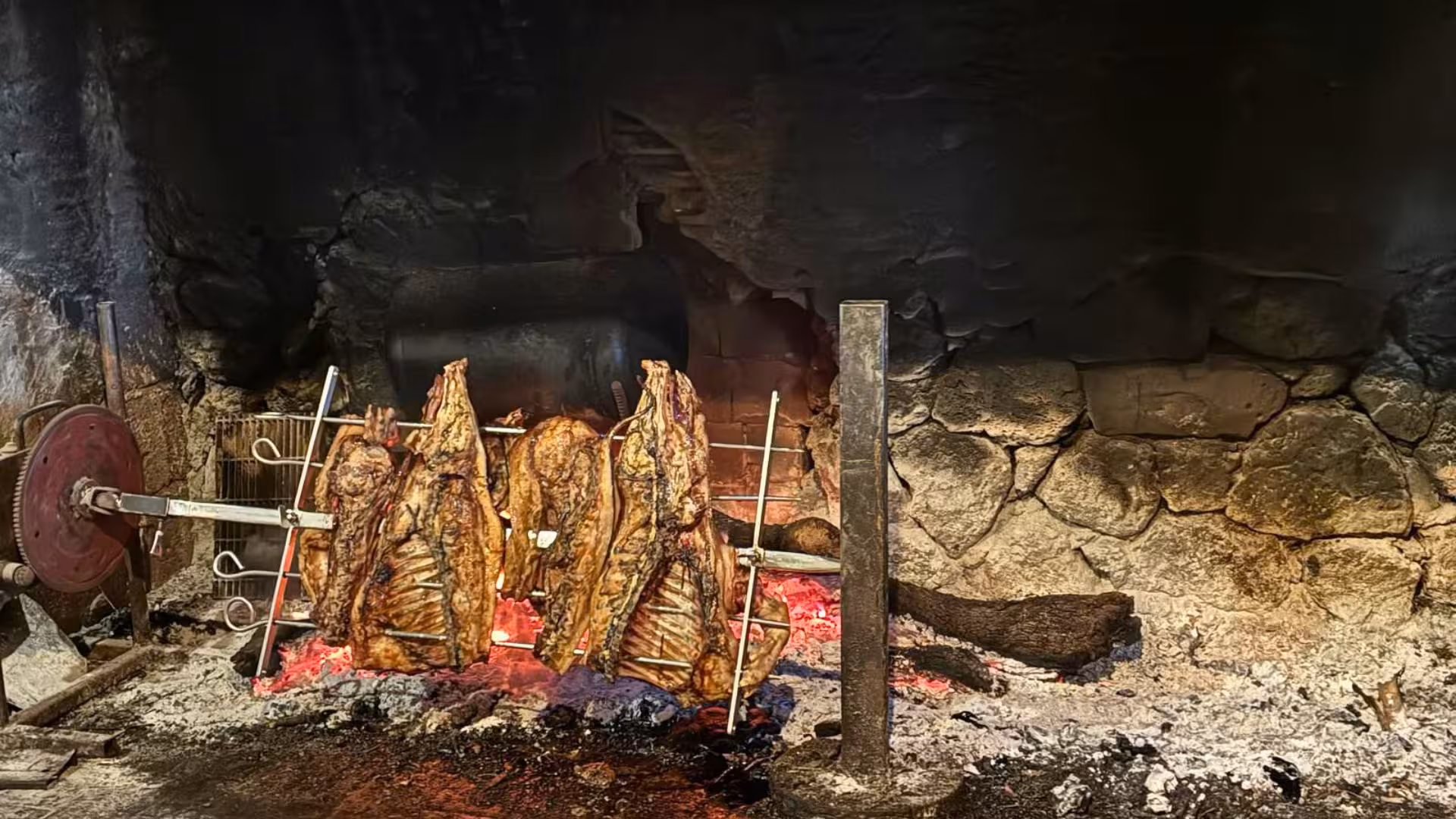 Traditional Sardinian roast meat cooking on an open fire during the Selvaggio Blu trek adventure.