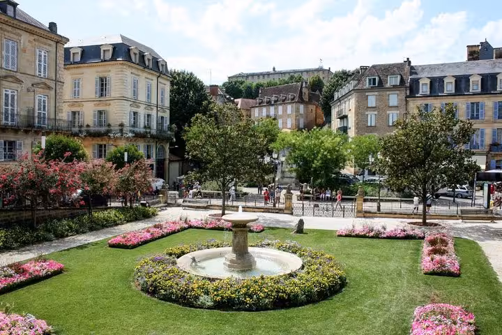 Ornate fountain and colorful flower gardens in a historic square in Sarlat-la-Canéda, France