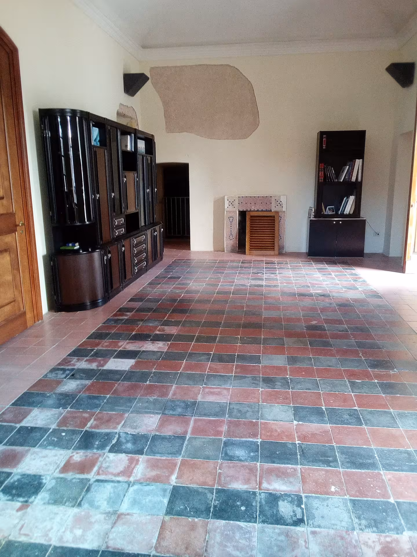 Spacious interior of Sassari's Ecomuseum with vintage tile flooring and classic shelves, ideal for cultural exhibits.