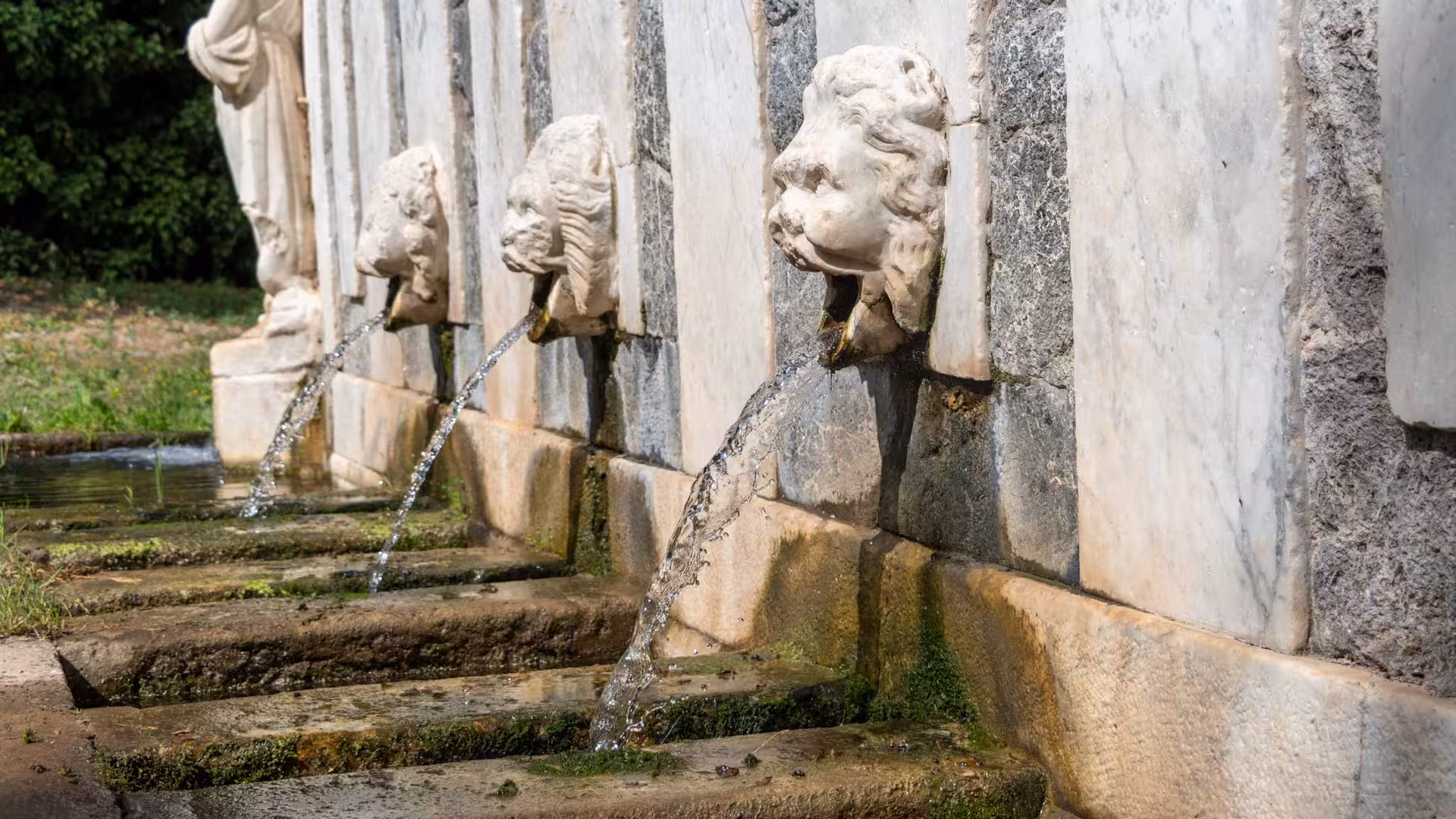 Historic lion-head fountains in Sassari's historic center, showcasing ornate stonework and flowing water features.