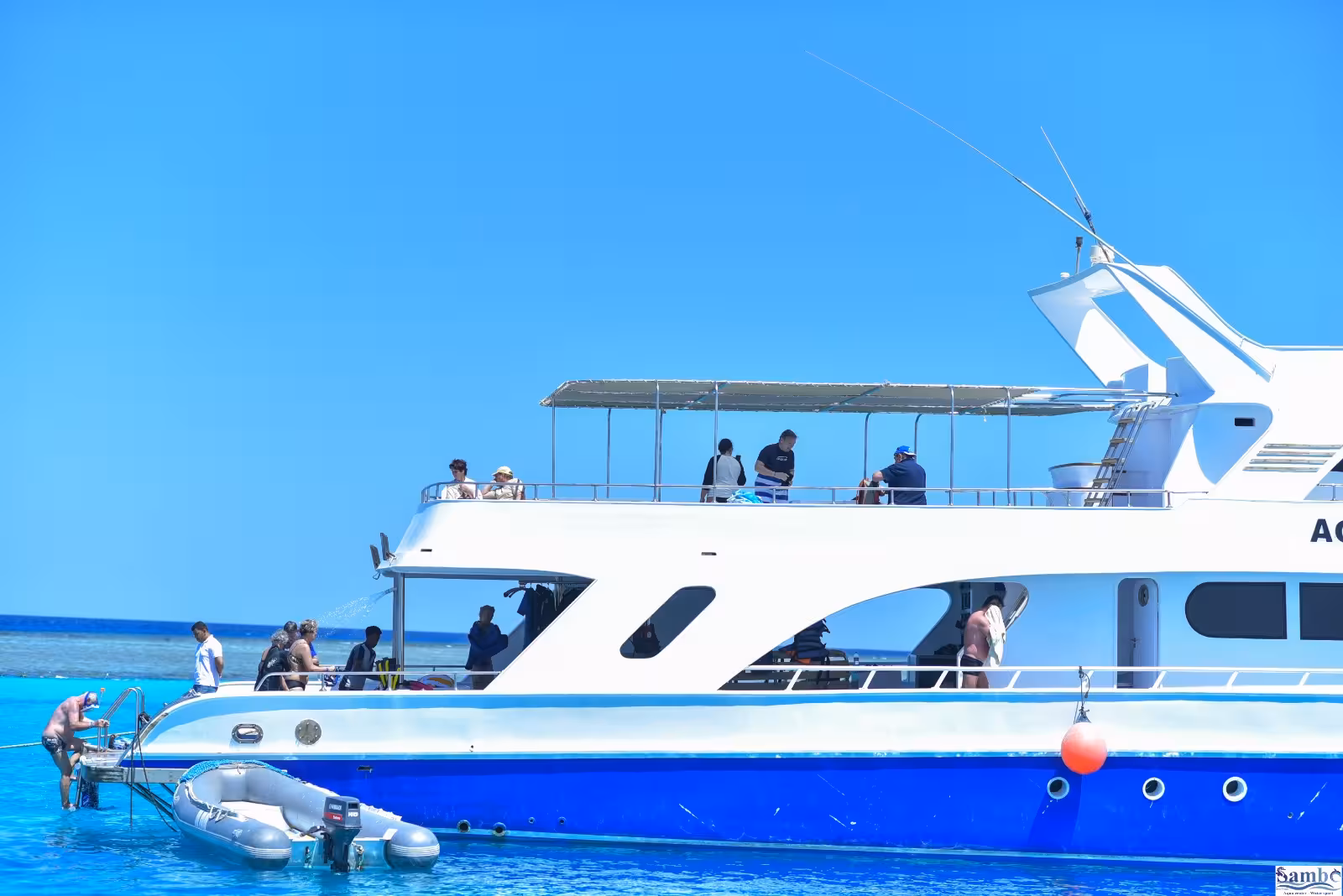 White and blue dive boat with snorkelers on deck at Sataya Reef in clear turquoise water