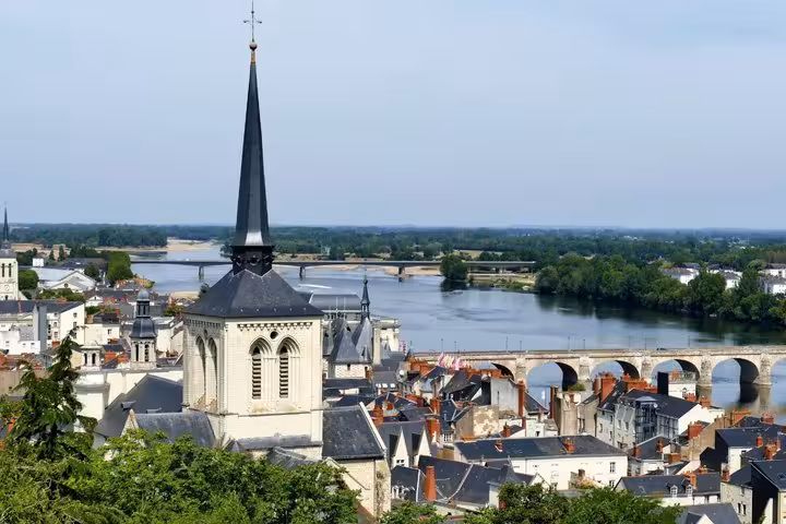 Aerial view of Saumur old town with church steeple, Loire River, and stone bridge in background