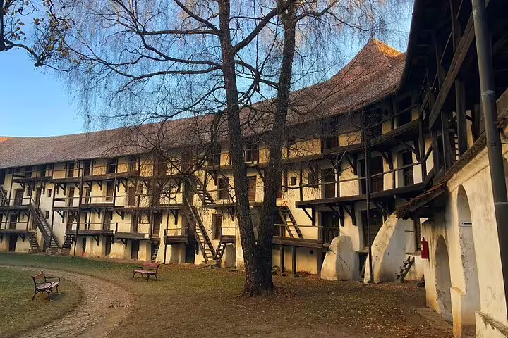 Courtyard of a Saxon fortified building with timber-framed galleries, wooden staircases, and bare trees in Brasov