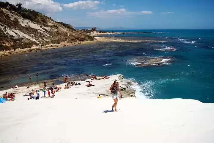 Traveler walking on the bright white Scala dei Turchi cliffs overlooking turquoise sea on an Agrigento private tour from Palermo