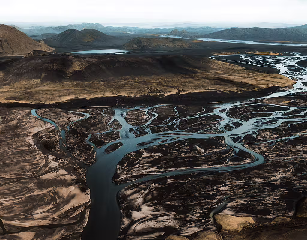 Aerial view of braided glacial rivers winding through black volcanic landscape in South Iceland