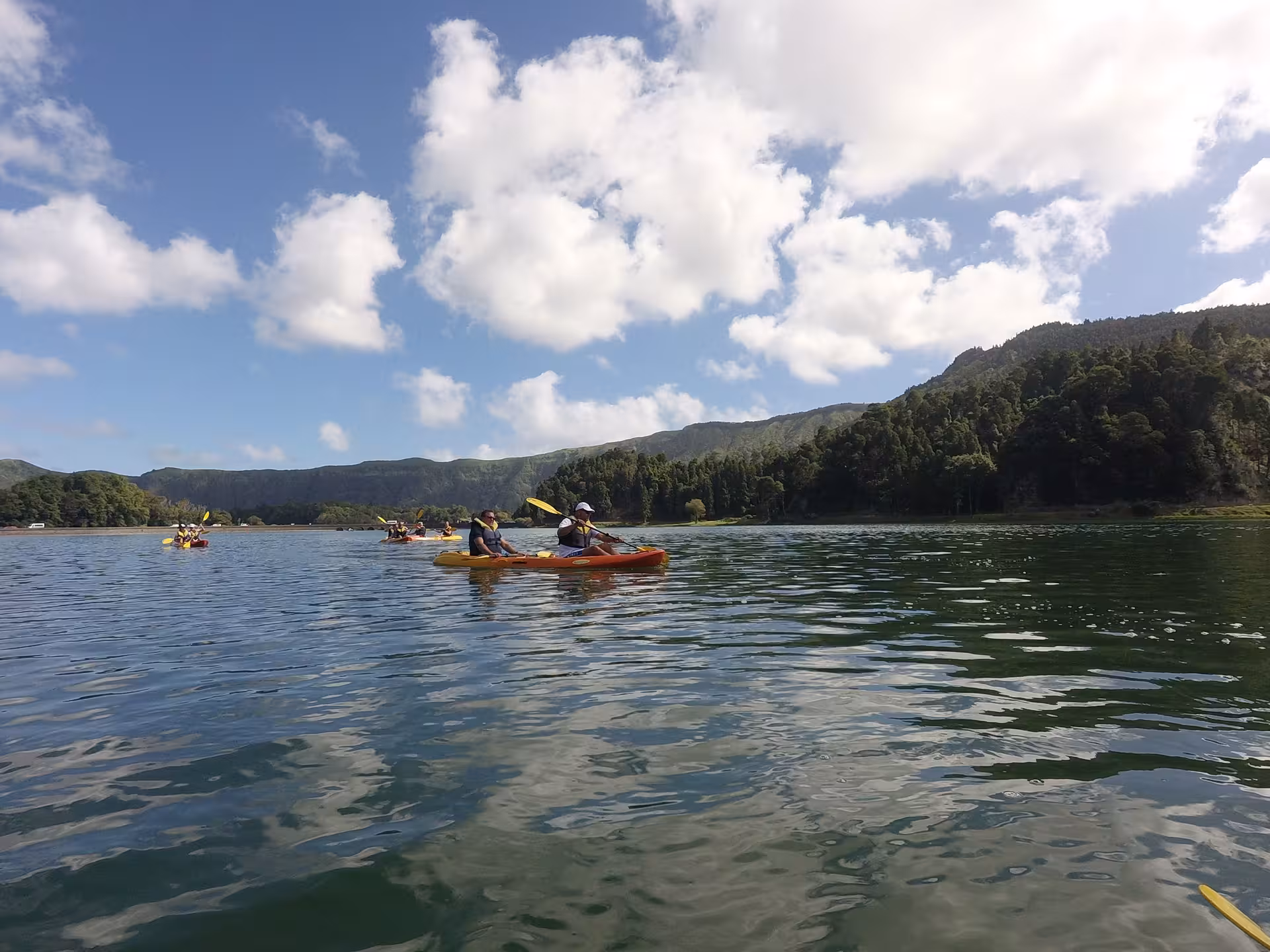 Small group canoeing across a scenic lake under blue skies, half-day guided paddle with transport included