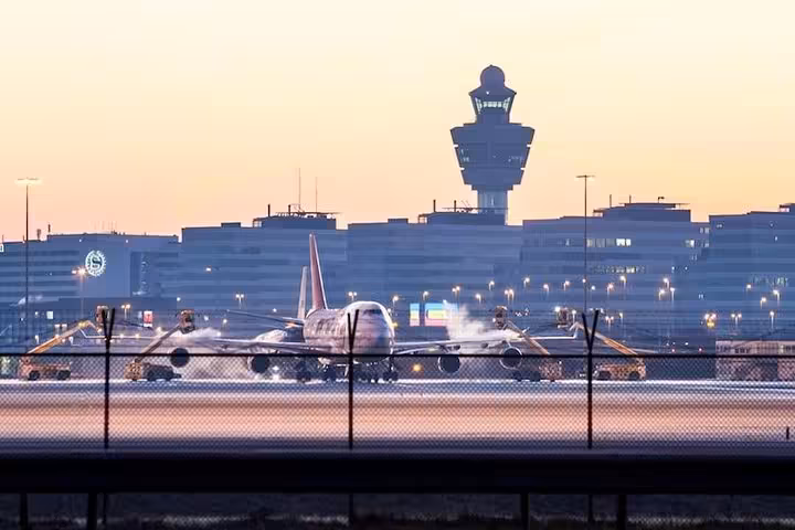 Evening runway scene at Amsterdam Schiphol, pre-booked private car transfer from airport to Brussels