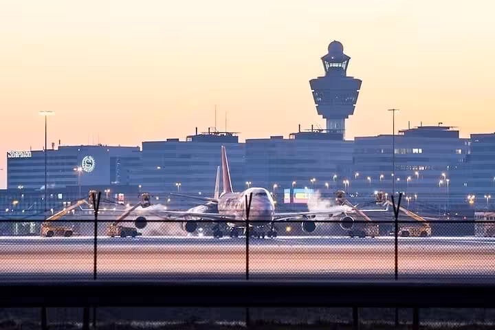 Schiphol Airport runway at dusk with plane and control tower, VIP Amsterdam airport arrival transfer service
