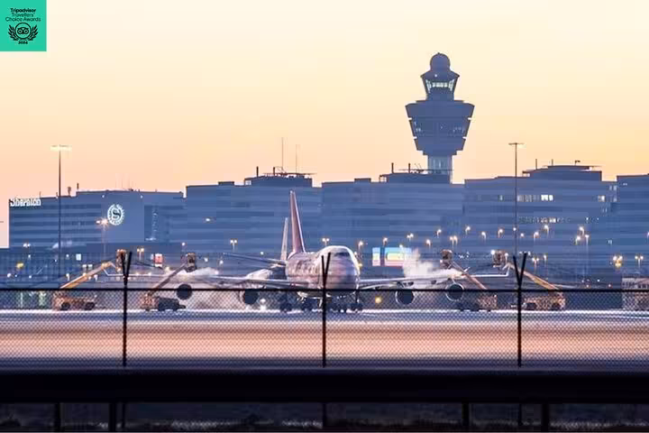 Aircraft at Amsterdam Schiphol Airport with control tower at dusk, ideal for private arrival transfer to city