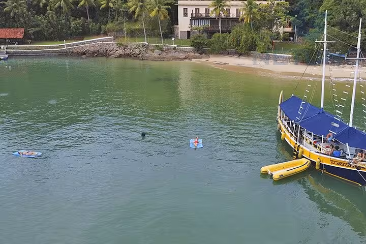 Schooner anchored near a sandy beach, with kayaks and paddleboards ready for a tropical island exploration.