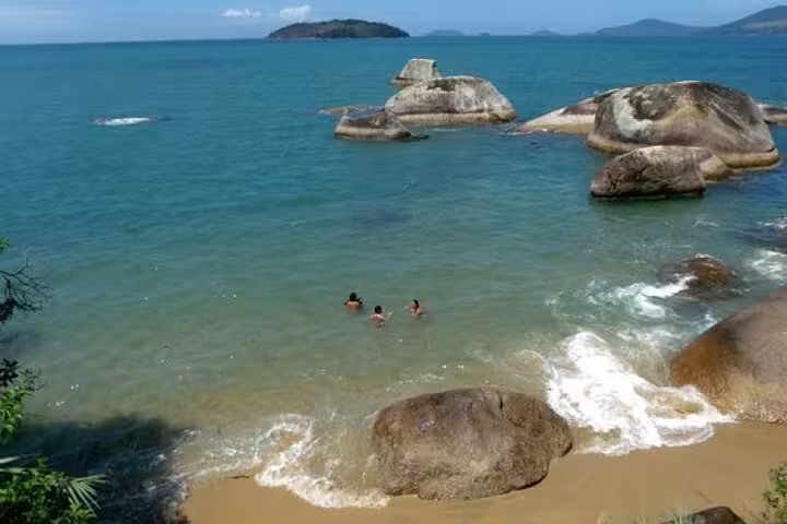 Pristine beach with turquoise waters and large rocks, perfect for swimming and exploring during a schooner excursion.
