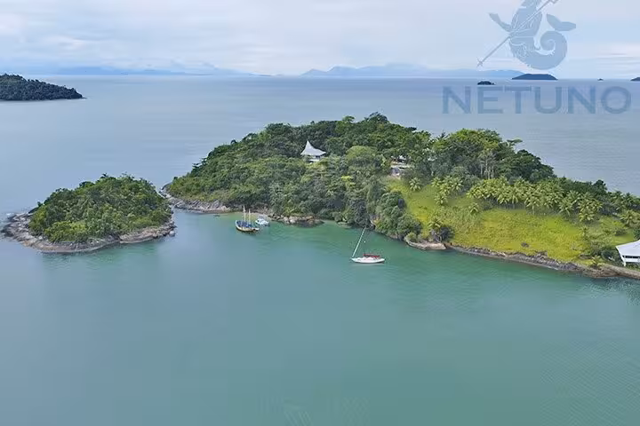 Scenic aerial view of a lush island with anchored schooner, ideal for paddleboarding and kayaking adventures.