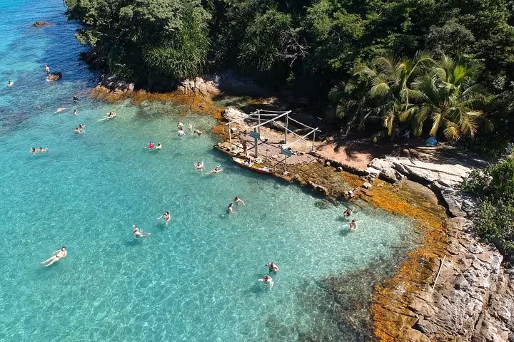 Tourists swim in the crystal-clear waters of Ilha Grande, showcasing the natural beauty of this schooner ride destination.