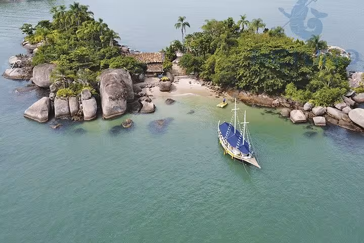 Aerial view of a schooner anchored near a lush island with sandy shores, offering standup paddle and kayak services.