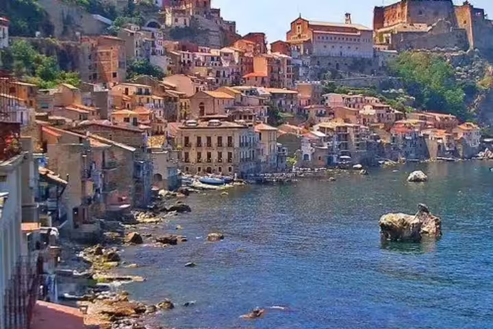Seaside view of Scilla, Calabria with pastel houses, rocky shoreline and historic Ruffo Castle overlooking the sparkling Tyrrhenian Sea