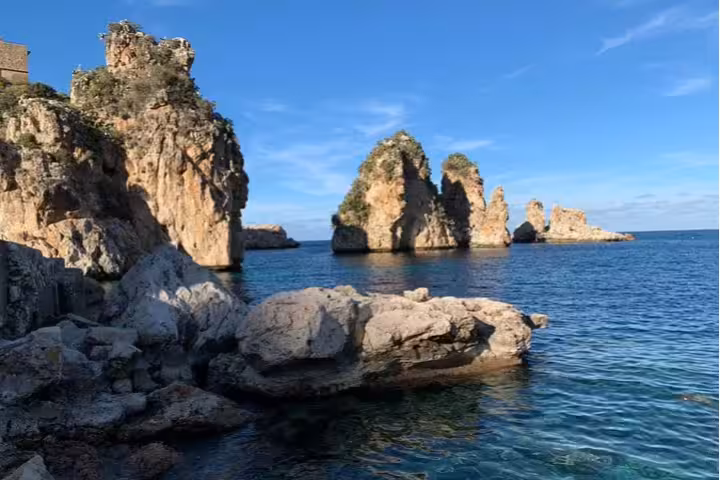 Dramatic sea stacks and clear blue water at Tonnara di Scopello viewed on a private coastal tour from Palermo